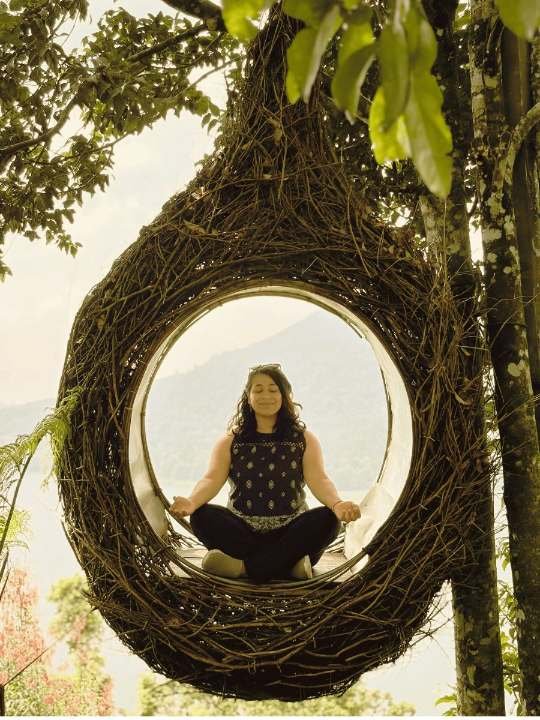 Aashna in a meditative seat inside a woven nest among the trees